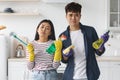 Bored asian man and woman holding cleaning tools