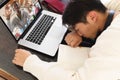 Bored asian teenage boy sleeping in front of laptop during online lecture on table at home Royalty Free Stock Photo