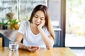 Bored asian woman looking disappointed at her smart phone while waiting someone Royalty Free Stock Photo
