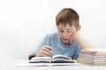 Bored boy doing homework at the desk. Schoolboy in glasses supports head with hand. Home schooling Royalty Free Stock Photo