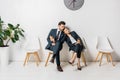 bored business colleagues with paper cups sitting on chairs Royalty Free Stock Photo