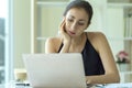 Bored businesswoman sitting on desk, working with laptop and staring at computer screen in the office Royalty Free Stock Photo