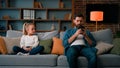 Bored child girl resting at home with father young dad using mobile phone little kid need attention looking at daddy Royalty Free Stock Photo