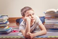 Bored child lying between piles of books