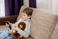 Bored child sitting on the sofa and watching tv. Royalty Free Stock Photo