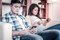 Bored couple resting on the coach and looking in their phones