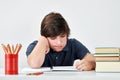 Bored and exhausted teenage boy sitting at the desk and concentrate on his homework