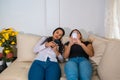 Bored friends using their smart phones sitting on a couch in the living room at home Royalty Free Stock Photo