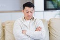 Young asian man sitting on sofa at home alone. Misses male sitting on the couch in apartment. Lonely guy indoors Royalty Free Stock Photo