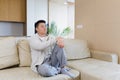 young asian man sitting on sofa at home alone. Misses male sitting on the couch in apartment. Lonely guy indoors