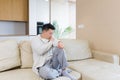 Bored friends young asian man sitting on sofa at home alone. Misses male sitting on the couch in apartment. Lonely guy indoors