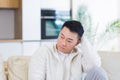 Bored friends young asian man sitting on sofa at home alone. Misses male sitting on the couch in apartment. Lonely guy indoors Royalty Free Stock Photo