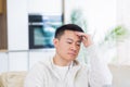 Bored friends young asian man sitting on sofa at home alone. Misses male sitting on the couch in apartment. Lonely guy indoors Royalty Free Stock Photo