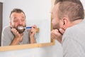 Bored guy brushing his teeth in bathroom