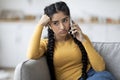 Bored Indian Woman Talking On Cellphone While Sitting On Couch At Home Royalty Free Stock Photo