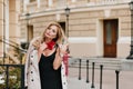 Bored lady with blonde curls looking away walking on the street alone in morning. Outdoor portrait of stunning european