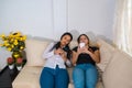 Bored latin friends using their smart phones sitting on a couch in the living room at home Royalty Free Stock Photo