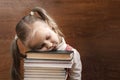 Bored learning. School Girl Sliping on books pile on dark Background. Royalty Free Stock Photo