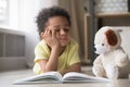 Bored little boy reading book lying on floor