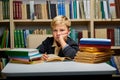 bored caucasian little boy tired of learning doing homework reading book