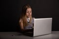 Bored little girl sitting on at the table and using computer . Royalty Free Stock Photo