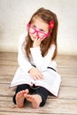 Bored little schoolgirl wearing glasses and reading book Royalty Free Stock Photo