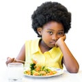 Bored looking african girl sitting with vegetable dish. Royalty Free Stock Photo