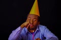 Bored looking man wearing blue shirt and hat sitting by table holding a single candle burning, sad expression facing Royalty Free Stock Photo