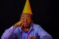 Bored looking man wearing blue shirt and hat sitting by table holding a single candle burning, sad expression facing Royalty Free Stock Photo