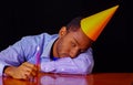 Bored looking man wearing blue shirt and hat sitting by table holding a single candle burning, sad expression facing Royalty Free Stock Photo