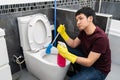 Bored man cleaning toilet bowl in bathroom Royalty Free Stock Photo