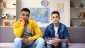Bored multiracial boys watching TV eating snacks, slow old technology connection Royalty Free Stock Photo