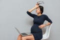 Bored pregnant business woman sitting over grey background Royalty Free Stock Photo