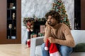 Bored and sad man sitting on sofa for christmas near christmas tree, hispanic depressed in living room lonely no friends Royalty Free Stock Photo