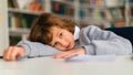 Bored schoolboy lying on desk during classroom lesson