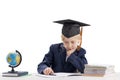 Bored schoolboy in students hat does his homework. Tired schoolboy isolated on white background Royalty Free Stock Photo