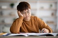 Bored schooler doing homework, leaning on his hand Royalty Free Stock Photo