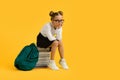 Bored Schoolgirl In Eyeglasses Sitting On Pile Of Books Over Yellow Background Royalty Free Stock Photo