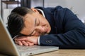 Bored sleepy business man worker working on laptop leaning on hands falling asleep at office table Royalty Free Stock Photo