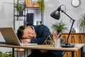 Bored sleepy business man worker working on laptop leaning on hands falling asleep at office table