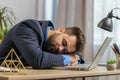 Bored sleepy Caucasian business man worker working on laptop computer, falling asleep at home office Royalty Free Stock Photo