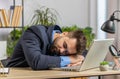 Bored sleepy Caucasian business man worker working on laptop computer, falling asleep at home office Royalty Free Stock Photo