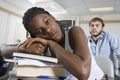 Bored Student Resting On Stack Of Books In Classroom