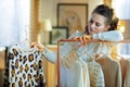 Bored stylish female choosing sweaters hanging on clothes rack