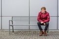 Bored teen boy making faces expressing negative thoughts sitting