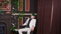 Bored teen student guy in white business suit sitting in a chair with a book by the fireplace Royalty Free Stock Photo