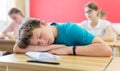 Bored teenage boy sleeping at desk in classroom during lesson Royalty Free Stock Photo