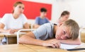 Bored teenage boy sleeping at desk in classroom during lesson Royalty Free Stock Photo