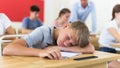 Bored teenage boy sleeping at desk in classroom during lesson Royalty Free Stock Photo