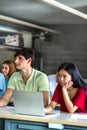 Bored and tired Asian female teen college student in class listening to lecture using laptop. Vertical. Copy space. Royalty Free Stock Photo